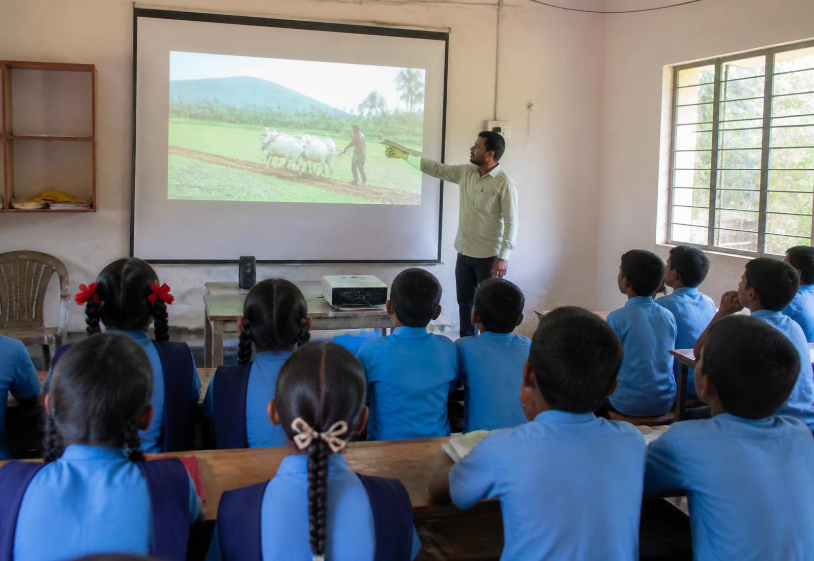 A teacher explaining a projected lesson to students in a classroom